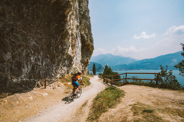 man cyclist on a mountain bike riding on a gravel bike route at a height near the Lago di Garda in summer in Italy