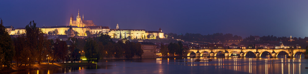 Night view of famous european Prague city - the capital of Czech republic with reflection in river Vltava and Charles Bridge. Panoramic view.