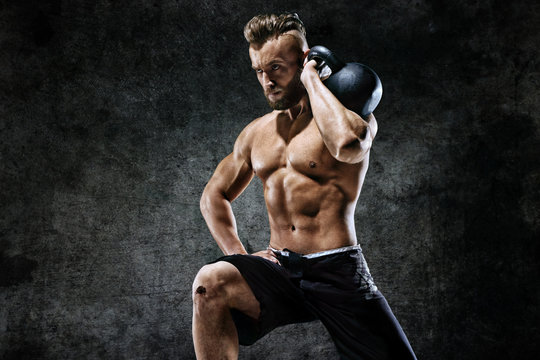 Young man working out with a kettlebell. Photo of man on dark background. Strength and motivation