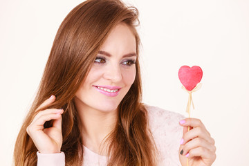 Flirty woman holding red wooden heart on stick