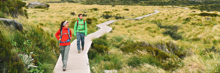 Hikers people hiking walking on Hooker Valley Track in summer lifestyle. Couple on travel holiday adventure. Banner panorama. New Zealand trampers backpacking on Mount Cook / Aoraki Hooker Valley.