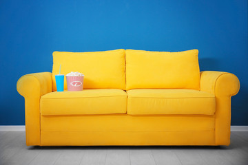 Yellow sofa with popcorn and drink in home cinema. Watching movie