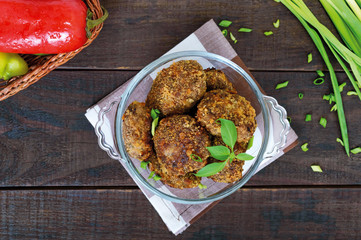 Small meat cutlets in a glass bowl on a dark wooden background. Top view.