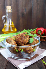 Small meat cutlets in a glass bowl on a dark wooden background.