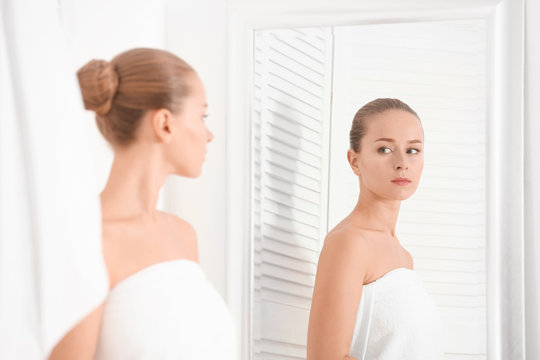 Beautiful young woman looking in mirror after taking shower