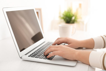 Young woman working with modern laptop at table, closeup