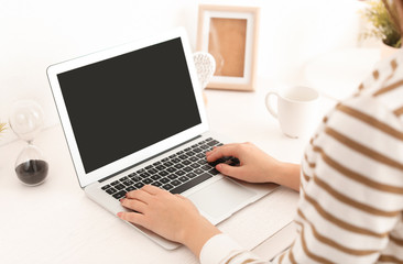 Young woman working with modern laptop at table