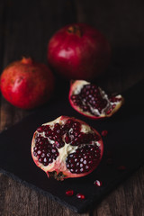Pomegranate fruit lies on the dark board.