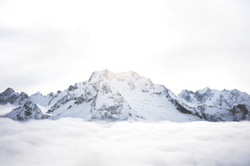 Obraz premium Snowy mountains above the clouds. Great winter massif of rocks