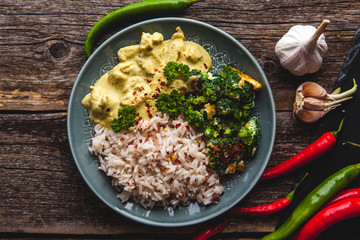 Handmade chicken curry tikka masala with basmati rice and broccoli on wooden table