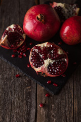 Pomegranate fruit lies on the dark board.