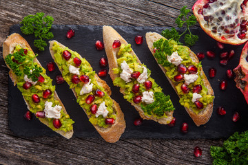 Toast with avocado and pomegranate on wooden table - 187239927