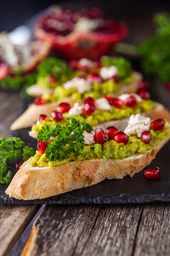 Toast with avocado and pomegranate on wooden table