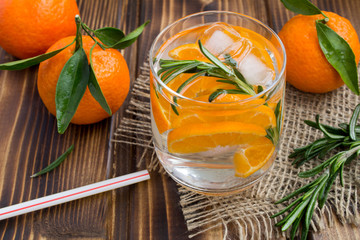 Detox water with mandarins and rosemary on the rustic wooden background