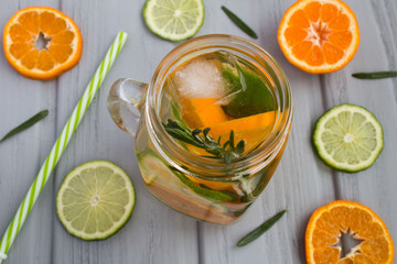 Detox water with mandarins,lime and rosemary on the grey wooden background.View from above.