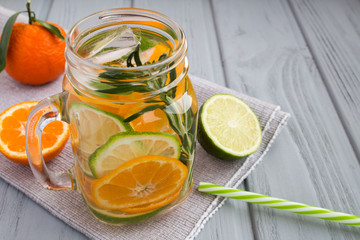 Detox water with mandarins,lime and rosemary on the grey napkin