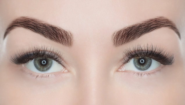 Procedure for eyelash extension. Beautiful woman with long eyelashes in a beauty salon. Look at the camera.
