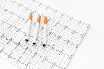 Danger of smoking. Cigarettes on cardiogram on white background