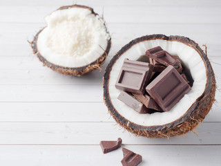 Fresh organic coconut broken into two parts with chocolate on a rustic wooden background