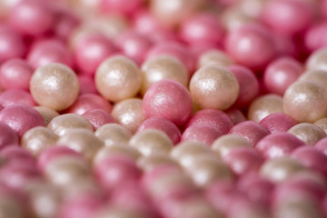 Closeup of a pile of pink and white sugar pearls (cake decor), side view