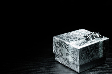 gift box wrapped with white ribbon on dark wooden background. with copy space.