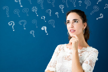 Young woman in a thoughtful pose with question marks