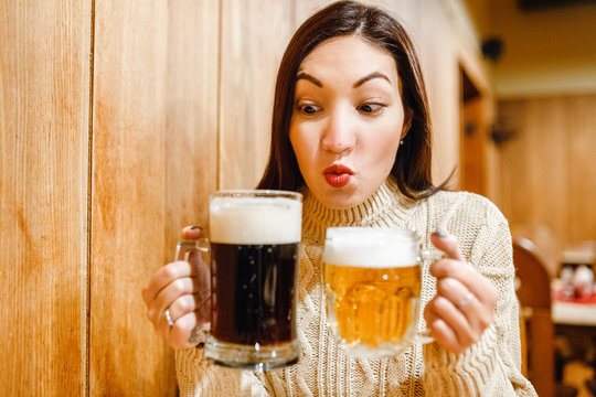 Funny woman holding two beer mugs in bar