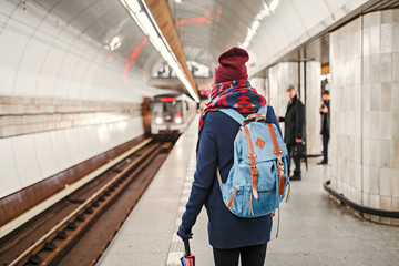 Rear view of a woman backpacker waiting for train arrival in metro or subway