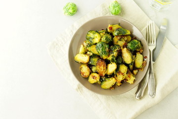 Homemade Roasted Brussel Sprouts with salt, pepper and onions in a beige plate on grey background. top view. copy space