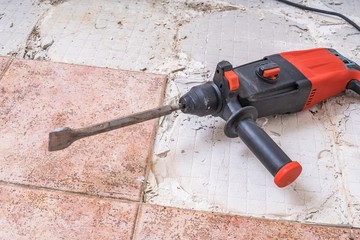 Removing old tiles. Jackhammer - drilling demolition hammer on floor.