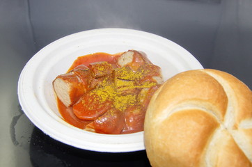 Currywurst mit Brötchen auf Pappteller