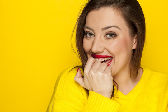 beautiful shy woman in a yellow blouse on a yellow background