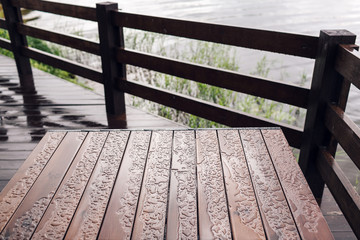 Cottage in forest near river with big wooden terrace. House on the water at the lake, a beautiful bank. Ideal place for vacation and holiday. Rain drops on table and chairs