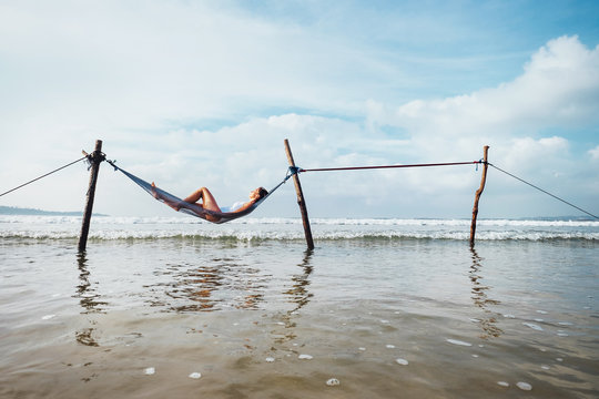 Woman relax lying in hammock swing over the ocean surf line