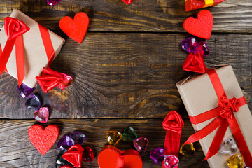 Gift boxes papier mache in the form of red hearts tied with satin ribbons and gifts Packed by craft paper on the wooden table.