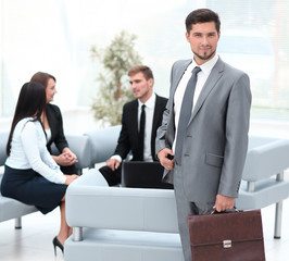 confident businessman with briefcase standing in the lobby of the office.