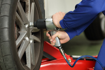 Car mechanic loosen wheel nuts in a workshop