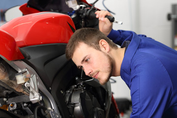 Motorbike mechanic listening engine to find failure