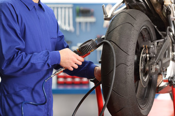 Motorbike mechanic checking tires air pressure