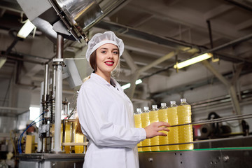 Cute young girl with a bottle of sunflower or olive oil on a production background.