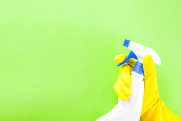 Hand in protective glove holding spray. green background copy space