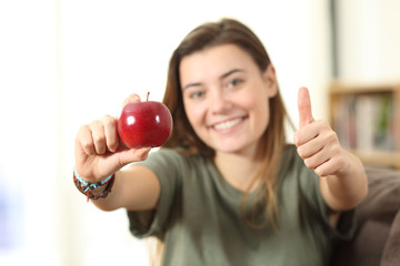 Healthy teen showing an apple at home