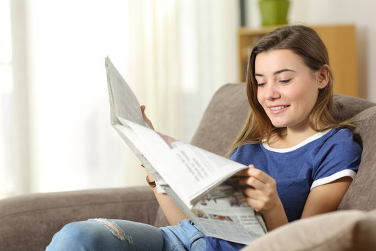 Teen reading a newspaper on a sofa at home