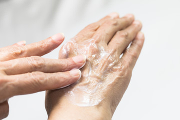 Senior woman hands with french manicure applying hand cream isolated on white background  © FATIR29