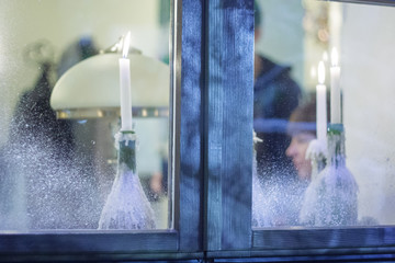 Frosted window with burning candles on the windowsill