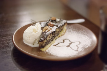 Piece of cake on a plate with ice-cream and butterfly-shaped icing (selective focus)