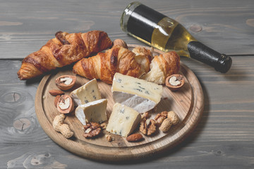 Wine bottles with cheese tasting and berries fruits on wooden background with copy space.