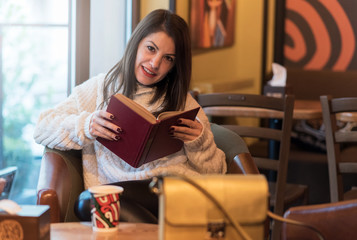 Attractive girl reading a book in a coffee shop