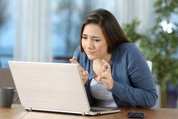 Woman crossing fingers checking on line content