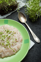 Bowl of homemade oatmeal with micro greens on a rustic table, healthy breakfast food